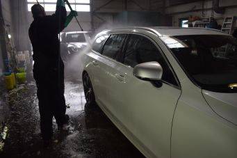 Binnenruimte autowasruimte met witte auto en hoge druk waterstraal bij autowassen in groningen