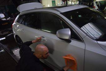 Foto van autopoetsen in binnenruimte met witte auto en open kofferbak, autowasstation en onderhoud, klein autopoets groningen