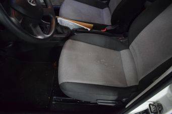 Interieur auto met grijs tweekleurige stoelen en zicht op stuur en versnellingspook, open deur en document tussen stoelen