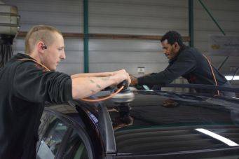 Binnenruimte waar twee mensen het dak van een auto professioneel polijsten in een autowerkplaats Klein Autopoets Groningen