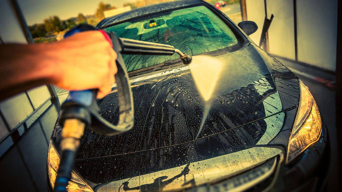 Auto met hogedrukreiniger schoongespoten op motorgedeelte water stroomt over motorkap permanent protector coating