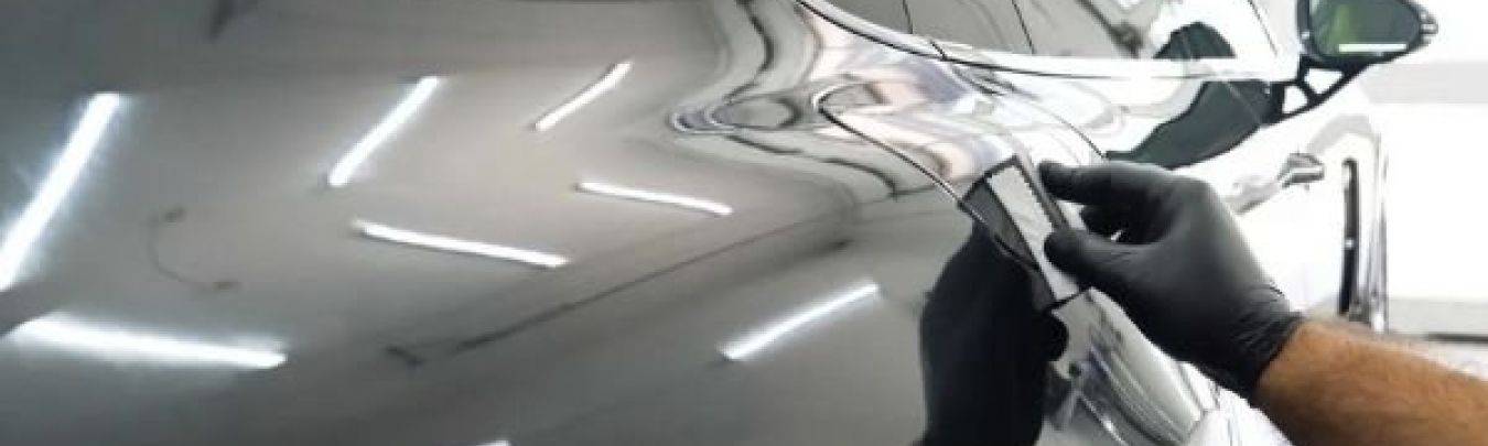 Close-up van hand met gereedschap die glascoating aanbrengt op glanzende zwarte auto deur in werkplaats