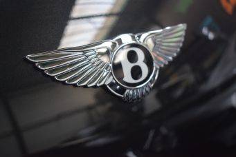Close-up van glanzend bentley logo met vleugels op motorkap in garage klein autopoets groningen