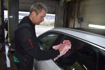 Auto schoonmaken met doek roze-witte strepen in garage reflectie zichtbaar autowas proces groningen