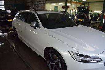 Witte auto in goed verlichte garage met glanzende vloer reflectie klein autopoets groningen