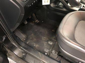 Intérieur bestuurderszijde met modderige vloerbedekking en voetafdrukken in auto volgens h2 klein autopoets groningen