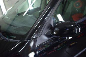 Close-up van glanzende zwarte autos voorruit, zijraam en buitenspiegel met reflecties bij Klein Autopoets Groningen