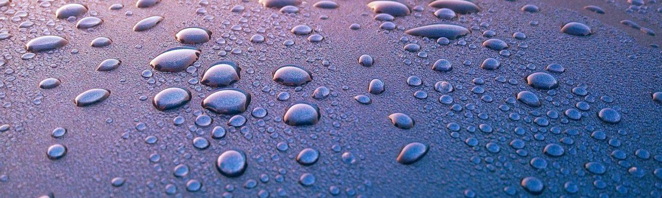 Close-up van glinsterende waterdruppels op een glanzend blauw-paars oppervlak bij overig diensten