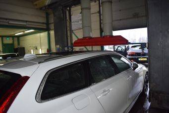 Witte auto in garage met rode afzuigkap voor uitlaatgassen h2 klein autopoets groningen