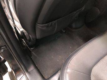 Interieur auto met zwarte vloermat tussen voorstoel en bestuurdersstoel vloer schoonmaak tips