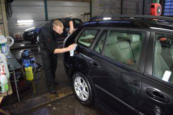 Autoverzorging in garage donker stationwagen wordt gepoetst achterzijde autocosmetica groningen