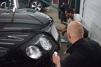 Garage-omgeving met zwarte auto, detailing en onderhoud door twee personen, autopoets in Groningen