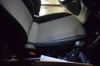 Interieur voertuig met bestuurdersstoel, handrem en versnellingspook, schakelschema zichtbaar, binnenkant auto detail