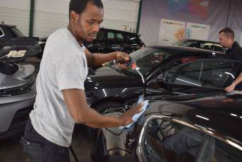 Binnenruimte met auto’s en actief autopoetsen in garage, benadrukt autopoetsen en auto-onderhoud in Groningen