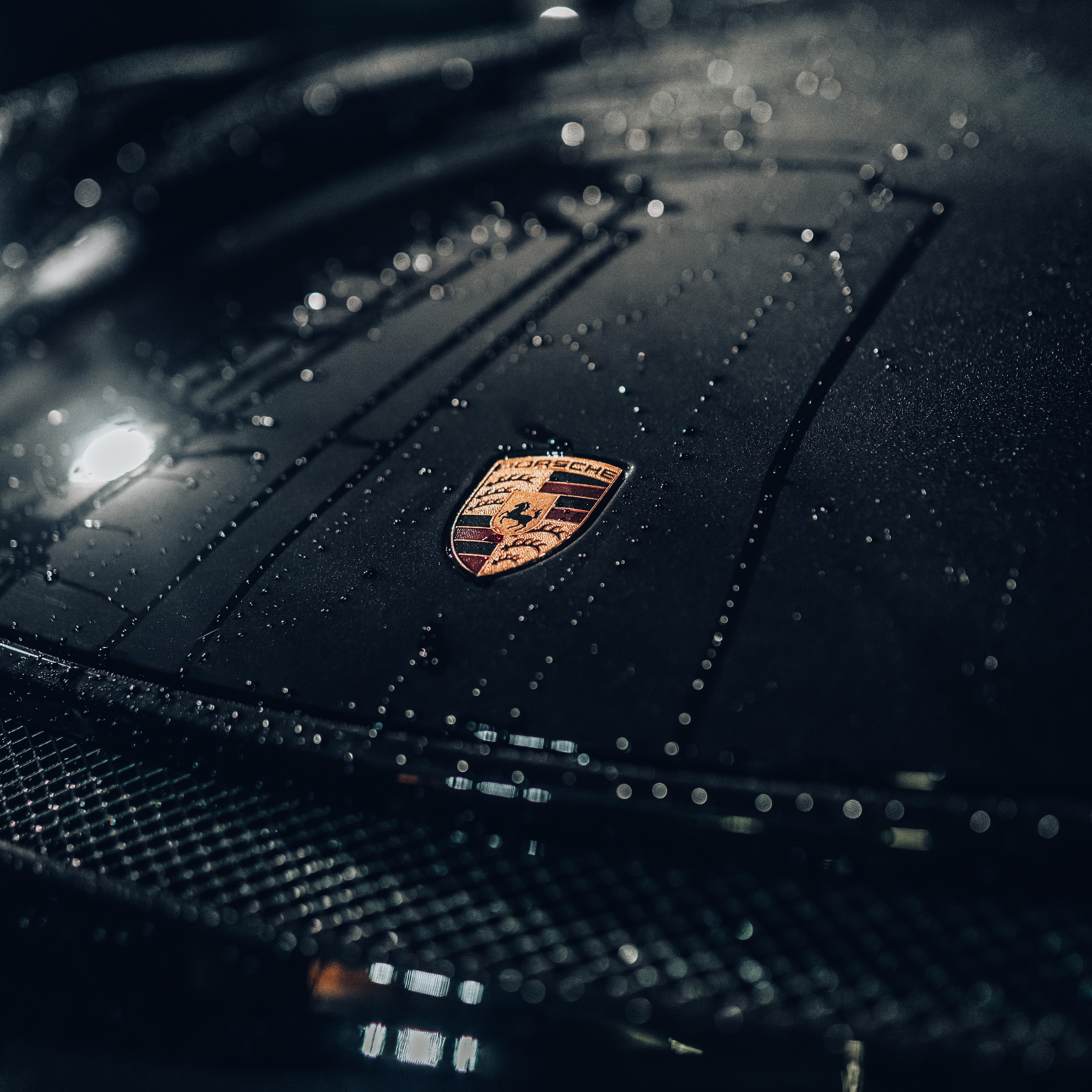 Close-up van natte porsche motorkap met embleem in donkere setting benadrukt glascoating prijs op aanvraag